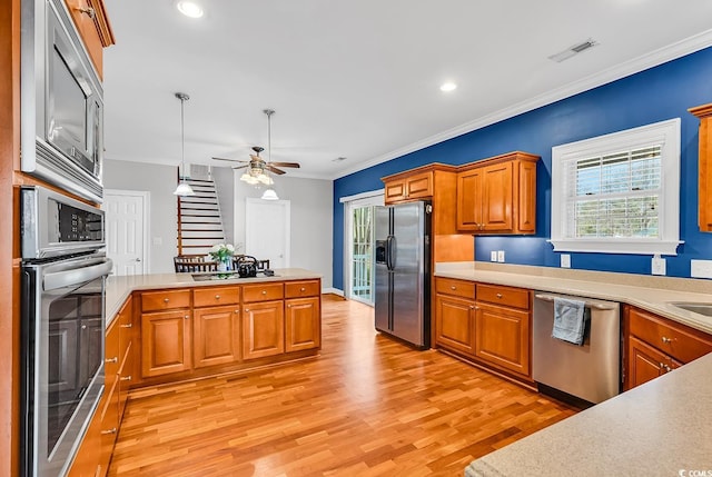 kitchen featuring light countertops, stainless steel appliances, light wood-type flooring, and a peninsula