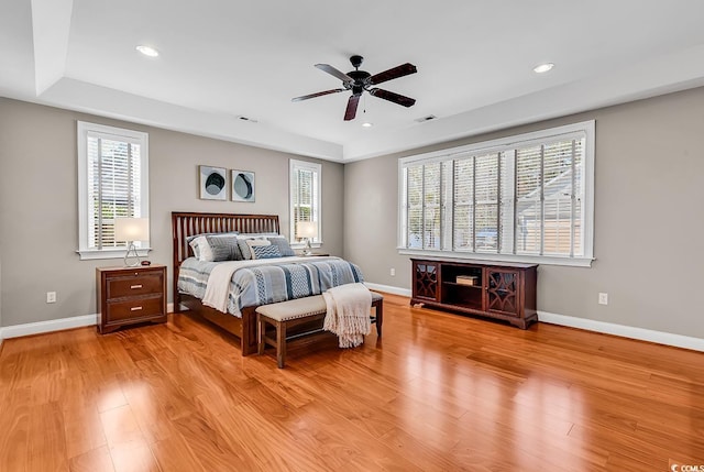 bedroom featuring baseboards, recessed lighting, wood finished floors, and a raised ceiling