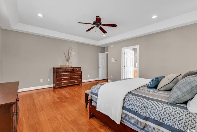 bedroom with recessed lighting, a ceiling fan, baseboards, light wood-type flooring, and a tray ceiling