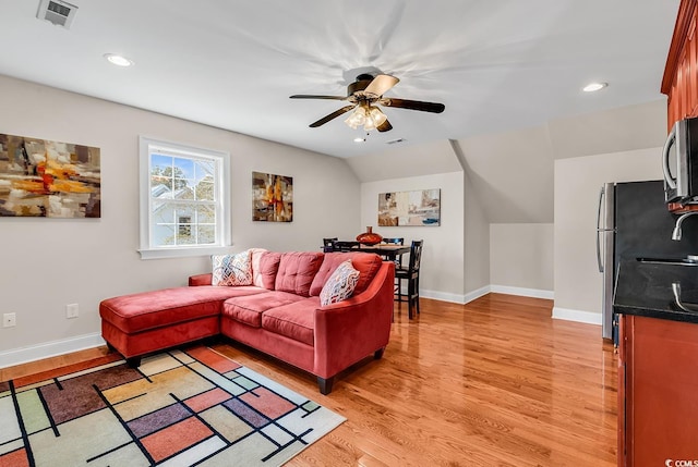 living room with ceiling fan, visible vents, baseboards, and light wood finished floors