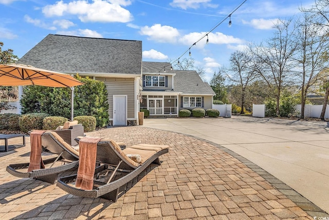 back of house featuring concrete driveway, a patio, fence, and a shingled roof