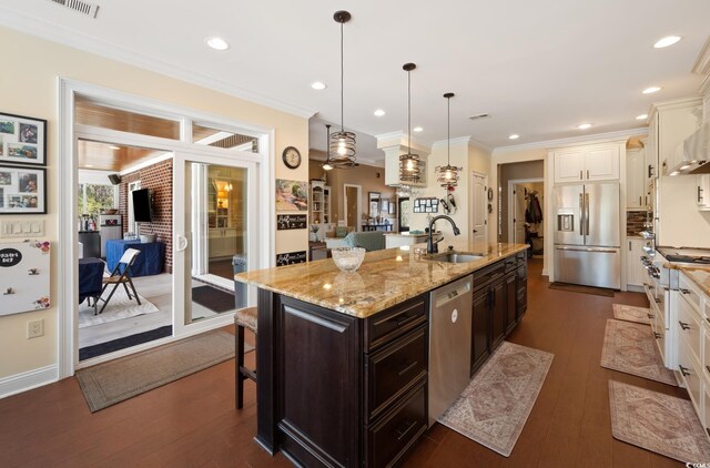 kitchen featuring crown molding, dark brown cabinetry, a breakfast bar area, stainless steel appliances, and a sink