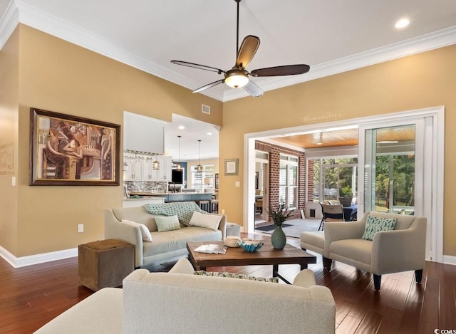 living area with crown molding, dark wood-style floors, a ceiling fan, and baseboards