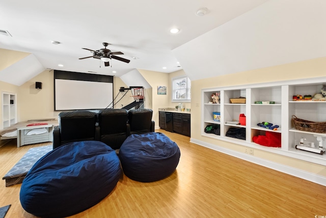 home theater room featuring a ceiling fan, vaulted ceiling, visible vents, and light wood-type flooring