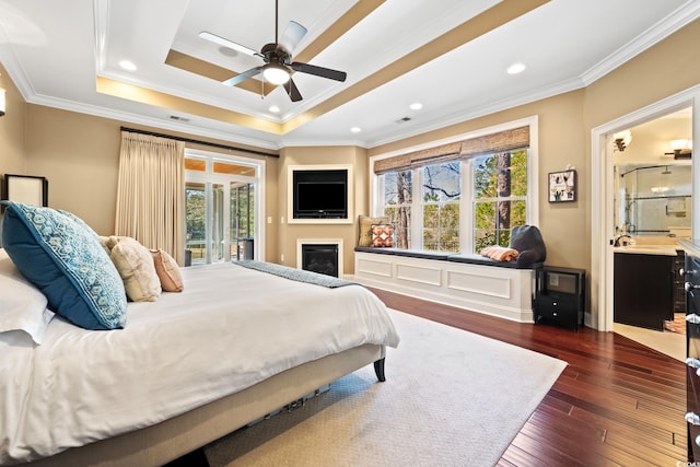 bedroom featuring a tray ceiling, multiple windows, access to exterior, and dark wood-style flooring