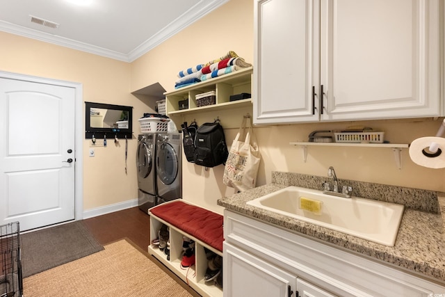 washroom with dark wood-style floors, visible vents, separate washer and dryer, a sink, and ornamental molding