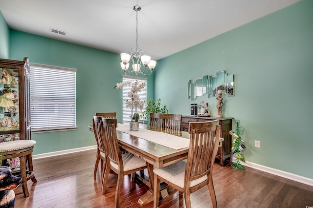 dining room with a chandelier, visible vents, baseboards, and wood finished floors