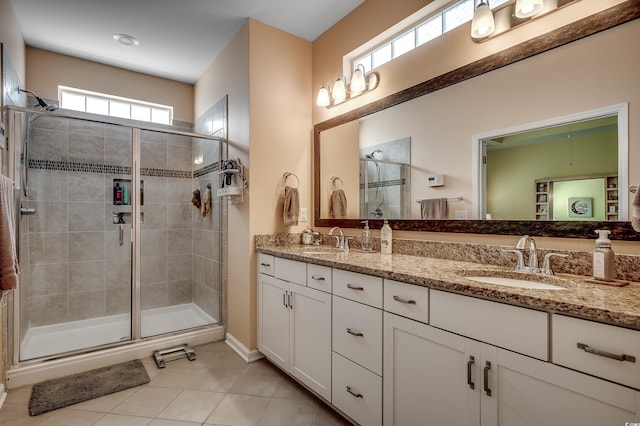 bathroom featuring tile patterned flooring, double vanity, a stall shower, and a sink