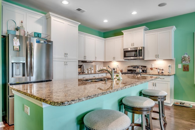 kitchen featuring tasteful backsplash, a breakfast bar area, white cabinets, stainless steel appliances, and a sink