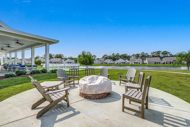 view of patio with a residential view, a fire pit, ceiling fan, and a water view