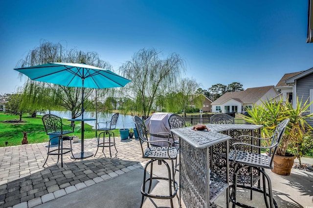 view of patio / terrace featuring a water view, outdoor dining space, and fence