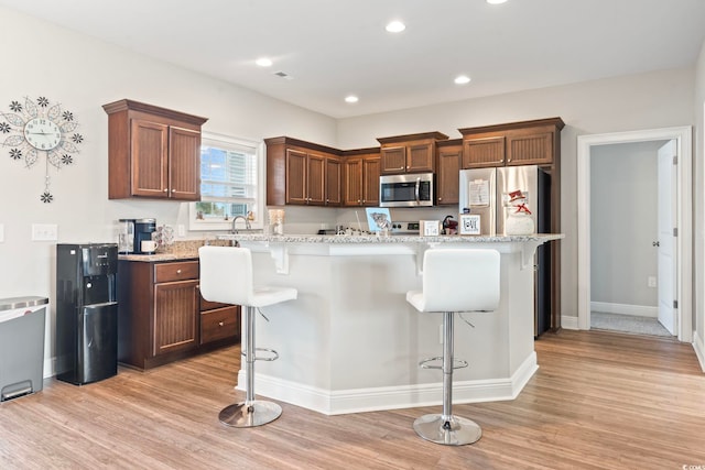 kitchen featuring light wood finished floors, stainless steel microwave, a center island, a kitchen bar, and recessed lighting