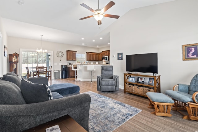 living room featuring recessed lighting, light wood-style floors, a healthy amount of sunlight, and ceiling fan with notable chandelier