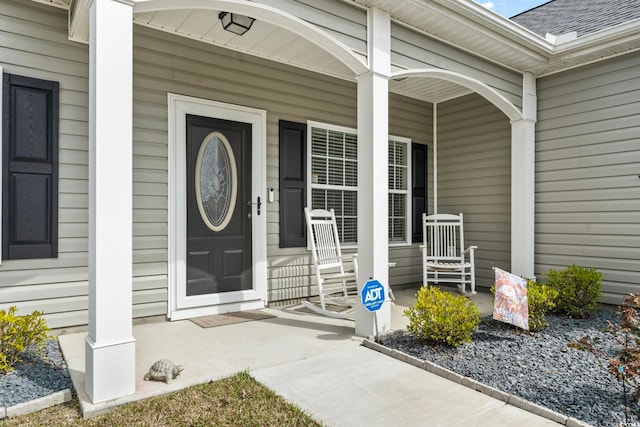 entrance to property featuring covered porch and roof with shingles