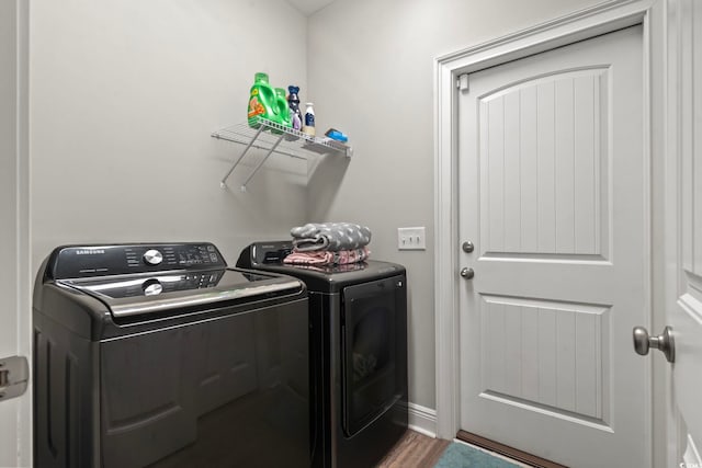 laundry area featuring washer and dryer, laundry area, wood finished floors, and baseboards