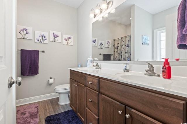 bathroom featuring a sink, baseboards, toilet, and wood finished floors