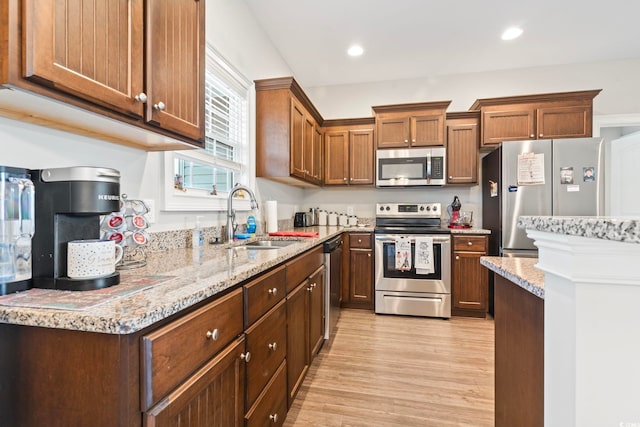 kitchen featuring light stone countertops, recessed lighting, a sink, stainless steel appliances, and light wood-type flooring