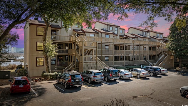 property at dusk featuring uncovered parking and stairs