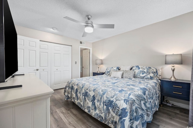bedroom featuring a textured ceiling, visible vents, wood finished floors, and a closet