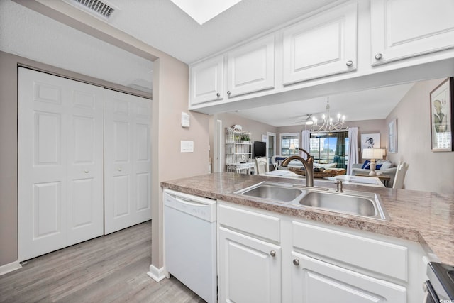 kitchen with light wood-style floors, white dishwasher, white cabinets, a sink, and a notable chandelier