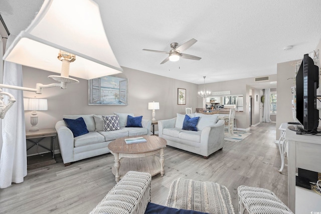 living area featuring light wood-type flooring and ceiling fan with notable chandelier