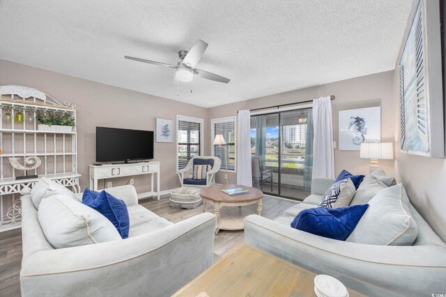 living room with baseboards, a ceiling fan, a textured ceiling, and wood finished floors
