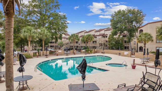 pool featuring a patio, a hot tub, and a residential view