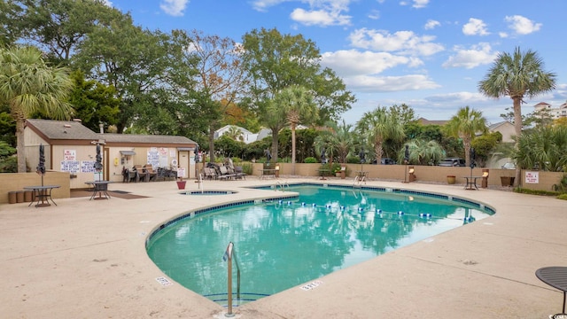 pool with fence, a hot tub, and a patio area
