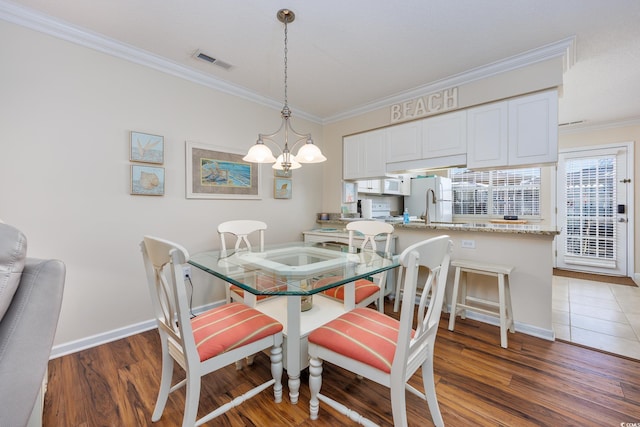 dining room featuring visible vents, crown molding, baseboards, an inviting chandelier, and wood finished floors