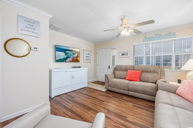 living room featuring baseboards, ceiling fan, ornamental molding, wood finished floors, and a textured ceiling