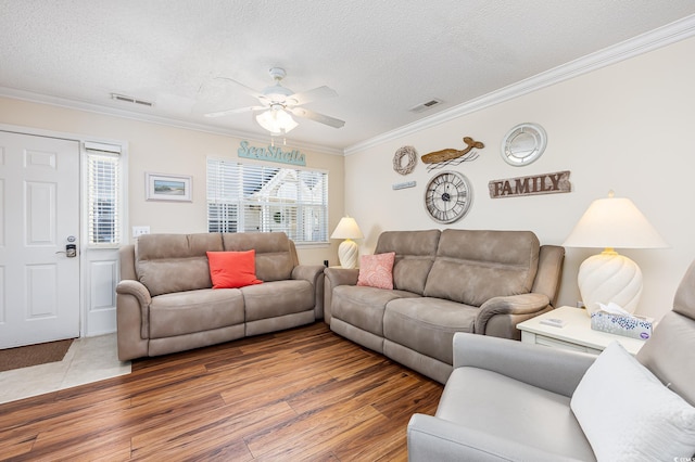 living area with wood finished floors, visible vents, a wealth of natural light, and ornamental molding