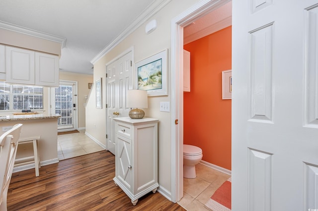 bathroom with toilet, wood finished floors, baseboards, and ornamental molding