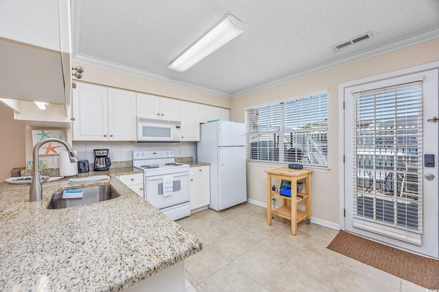 kitchen with visible vents, white appliances, white cabinetry, and a sink