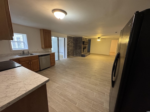 kitchen featuring a fireplace, open floor plan, light countertops, freestanding refrigerator, and stainless steel dishwasher