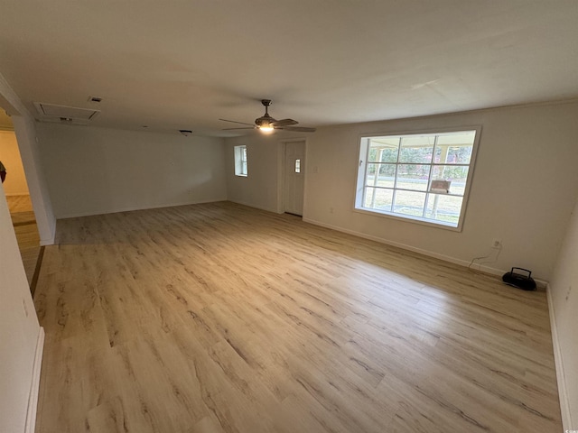 spare room featuring light wood-type flooring, baseboards, a ceiling fan, and a healthy amount of sunlight