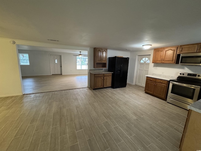 kitchen with open floor plan, appliances with stainless steel finishes, light countertops, and light wood-style flooring