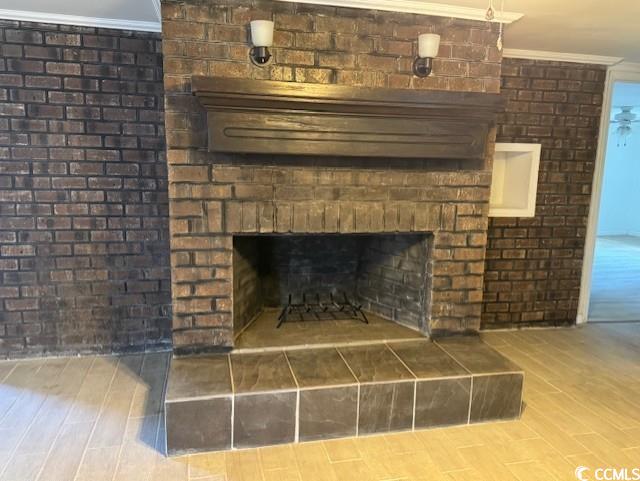 room details with crown molding, wood finished floors, and a brick fireplace