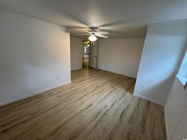 unfurnished room with baseboards, a ceiling fan, and wood finished floors