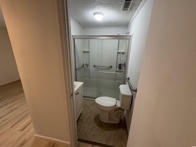 full bath with crown molding, a shower stall, a textured ceiling, visible vents, and toilet