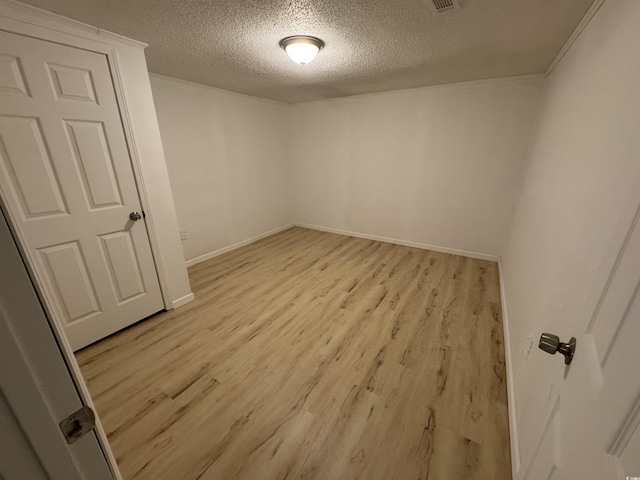 empty room featuring light wood-style floors, a textured ceiling, and baseboards
