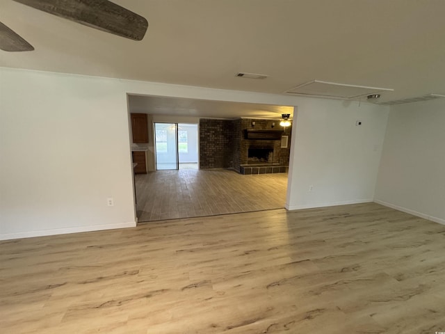 unfurnished room featuring baseboards, a fireplace, attic access, visible vents, and wood finished floors