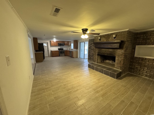 unfurnished living room featuring light wood-type flooring, a tiled fireplace, a ceiling fan, crown molding, and visible vents