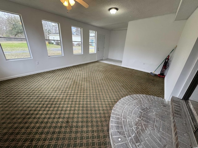 carpeted spare room featuring a textured ceiling, baseboards, and a ceiling fan