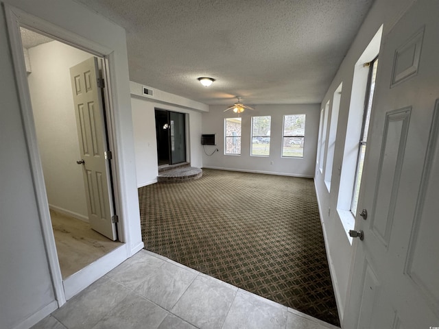interior space featuring baseboards, carpet flooring, a textured ceiling, visible vents, and ceiling fan