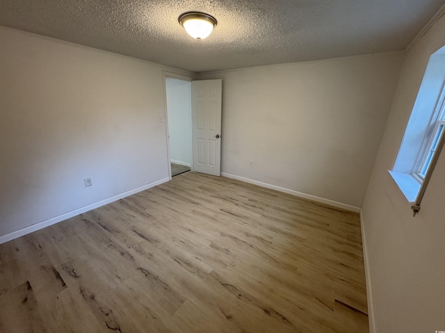 empty room featuring baseboards, wood finished floors, and a textured ceiling