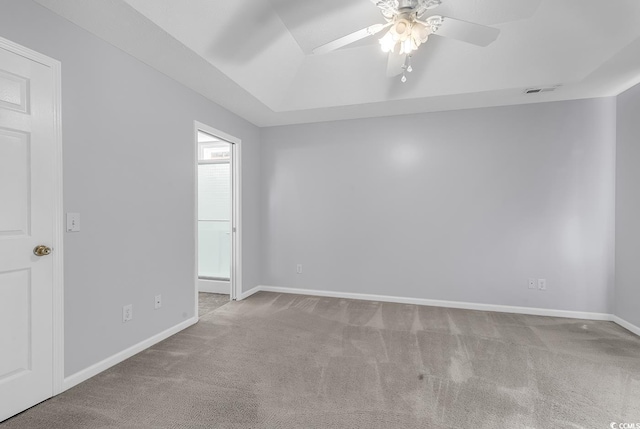 spare room with a raised ceiling, carpet, baseboards, and ceiling fan