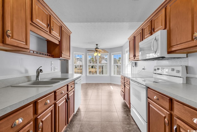 kitchen with ceiling fan, white appliances, brown cabinetry, a textured ceiling, and a sink