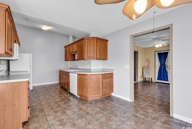 kitchen featuring a sink, light countertops, ceiling fan, white appliances, and brown cabinets