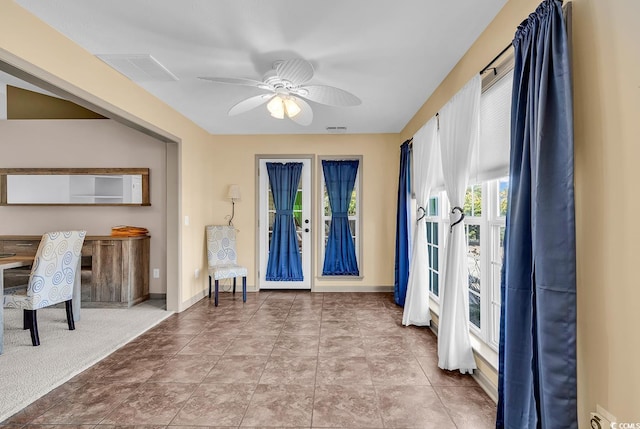 foyer entrance with baseboards, a ceiling fan, and visible vents