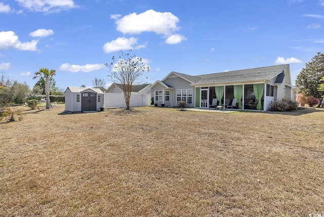 rear view of property with a shed, a yard, a patio area, fence, and an outdoor structure